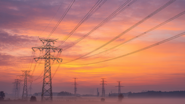 Torres de la red de distribución eléctrica en una zona rural al amanecer.